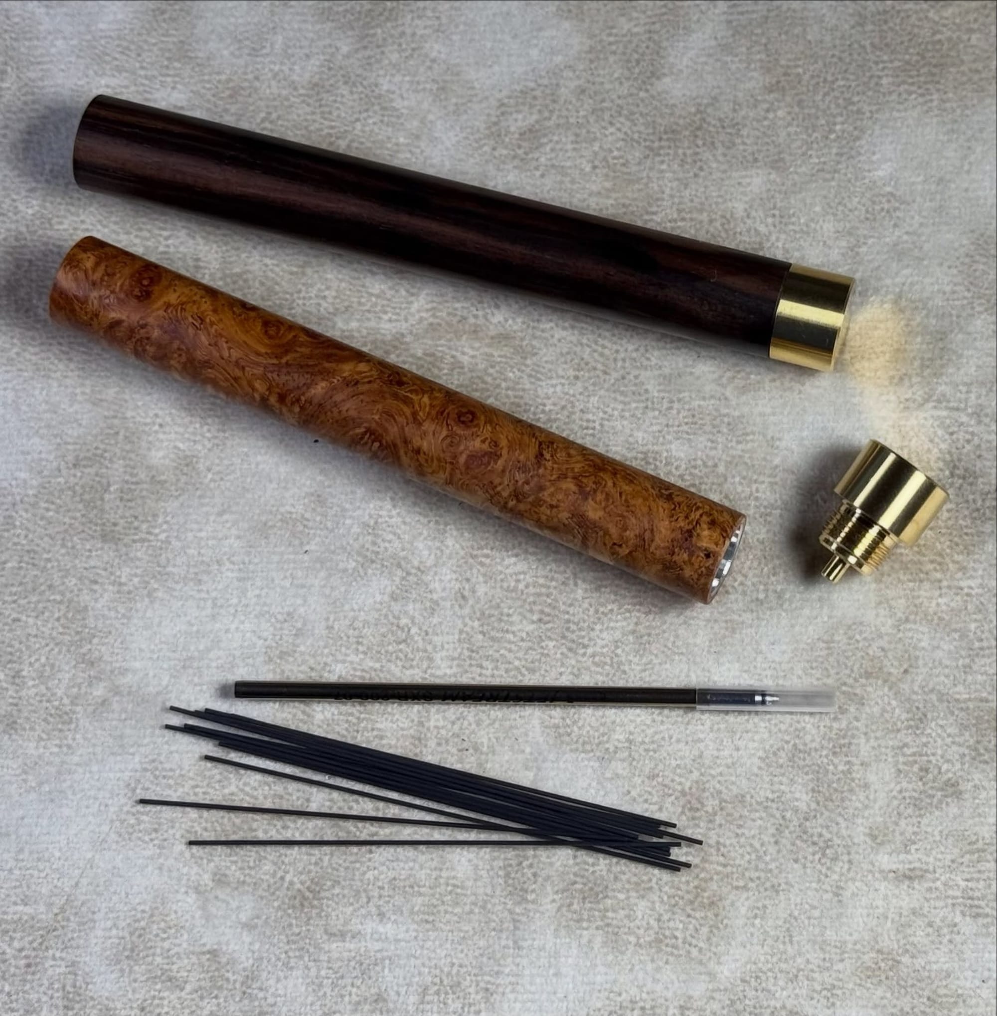 Open long wooden refill cases with pencil leads and a metal pen refill.